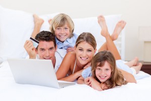 Enthusiastic family buying online lying down on bed