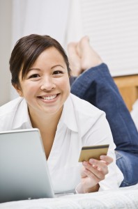 Beautiful asian woman holding a credit card and using a laptop.