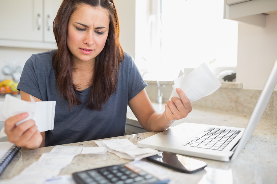 Young woman getting stressed over finances in kitchen