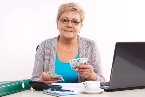 Elderly senior woman counting cash for utility bills at her home