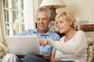 Mature Couple Sitting On Sofa At Home Using Laptop