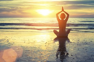 Silhouette of yoga woman meditating on the ocean beach. Fitness.